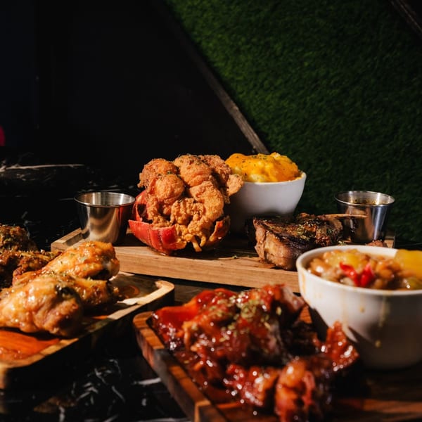 A soul food feast featuring fried lobster, mac and cheese, steak, chicken, and stew.